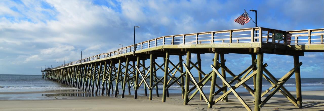 Entire Oak Island Pier from the beach with American flag flying
